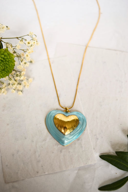 Heart-shaped necklace with gold heart and turquoise border on a light background